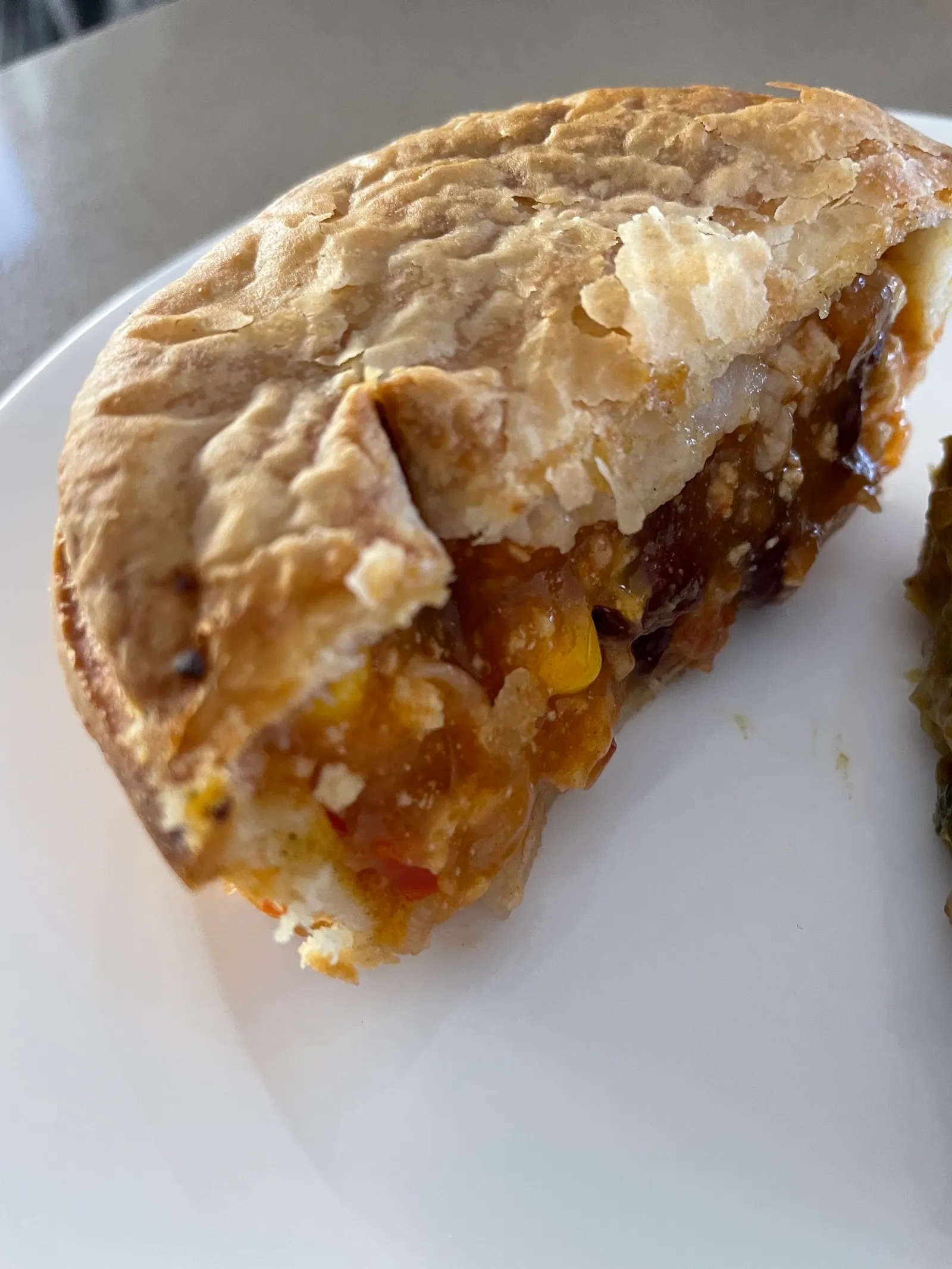 Halved curry pie on a white plate showing chunky filling and flaky crust