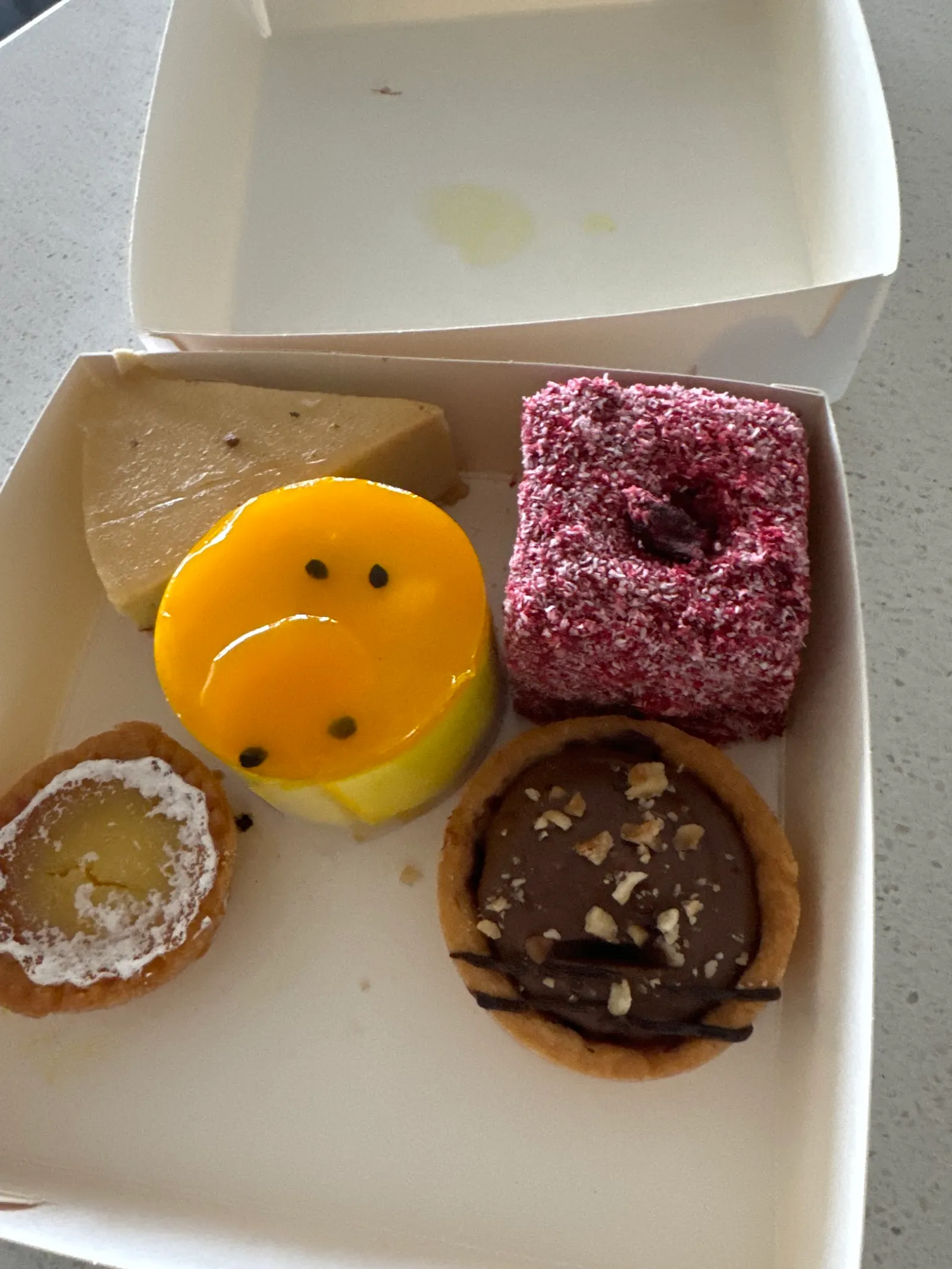 Box of four assorted mini cakes including lamington, lemon tart and passionfruit cake